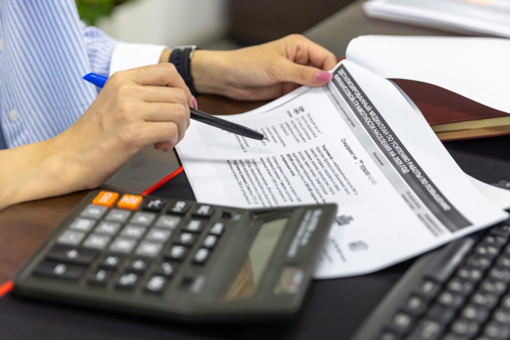 Hands using a calculator next to financial papers