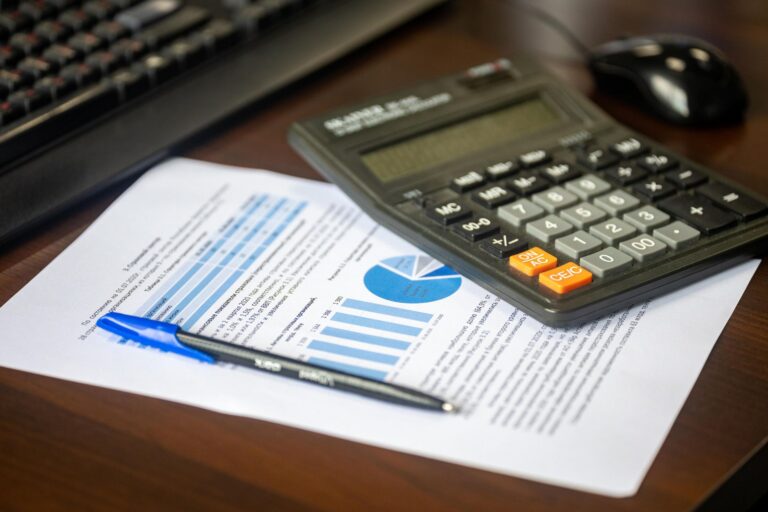 Calculator, pen, and financial report on a desk used to calculate DCAA provisional billing rates