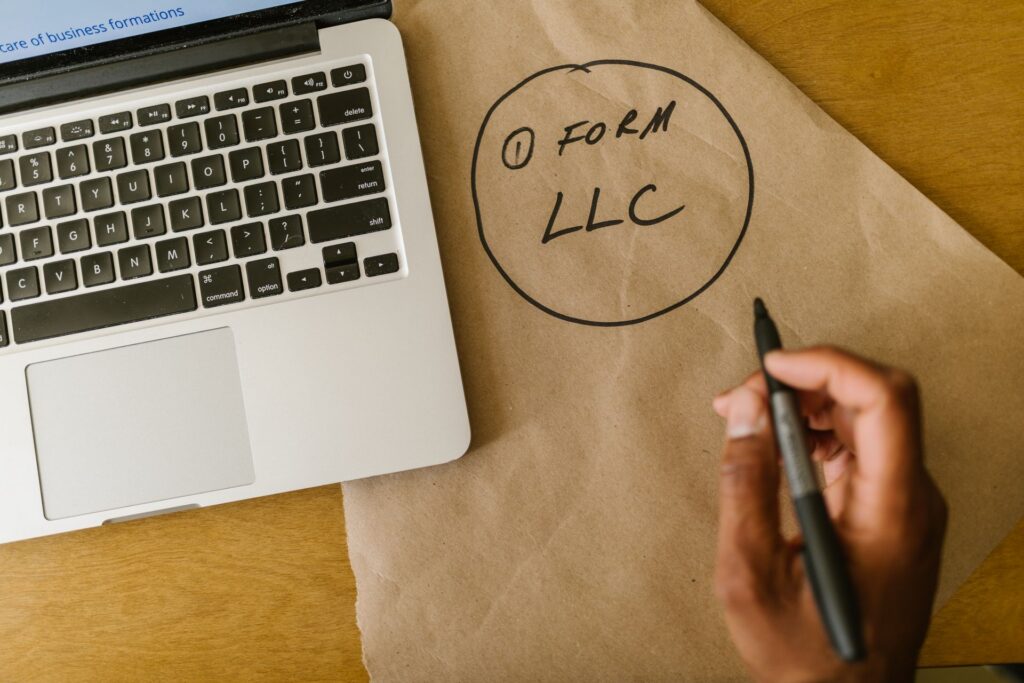 Business owner writing Form LLC on paper next to a laptop while planning business entity selection